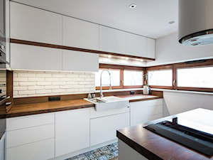 Woronicza - Średnia otwarta zamknięta biała z zabudowaną lodówką z nablatowym zlewozmywakiem kuchnia w kształcie litery l z wyspą lub półwyspem z oknem, styl nowoczesny - zdjęcie od Qbik Design