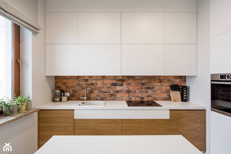 RYDYGIERA - Średnia zamknięta biała z zabudowaną lodówką z nablatowym zlewozmywakiem kuchnia w kształcie litery l z oknem - zdjęcie od Qbik Design