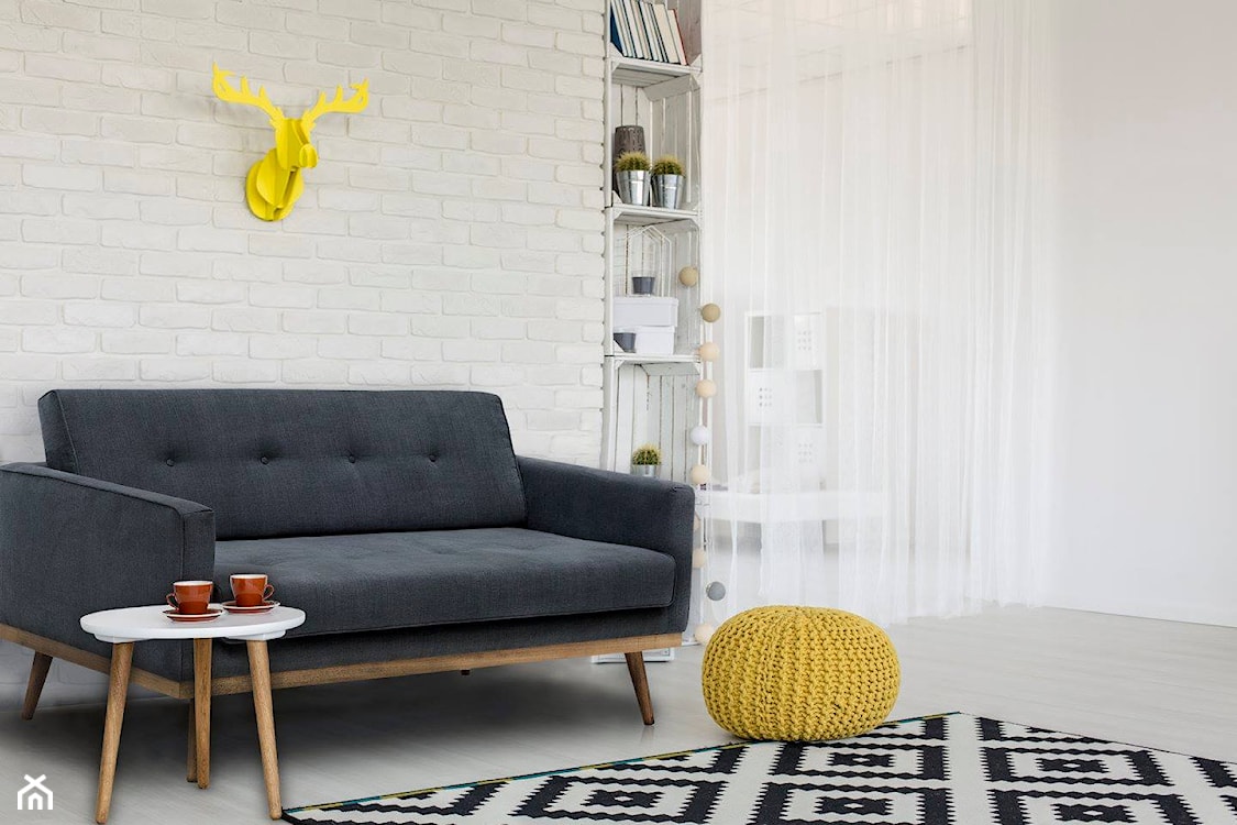 szara sofa, dywan w romby, żółty puf, biały stolik