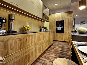 Kuchnia KOMANDOR - Duża otwarta z salonem żółta z zabudowaną lodówką z nablatowym zlewozmywakiem kuchnia dwurzędowa z kompozytem na ścianie nad blatem kuchennym - zdjęcie od Komandor - Wnętrza z Charakterem