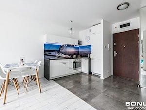 Apartament osiedle Bursztynowe Kołobrzeg - Otwarta z salonem z kamiennym blatem biała z zabudowaną lodówką z lodówką wolnostojącą z nablatowym zlewozmywakiem kuchnia w kształcie litery l z oknem, styl nowoczesny - zdjęcie od PIOTR RUMIANOWSKI ARANŻACJE KUCHNI