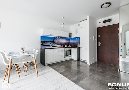 Apartament osiedle Bursztynowe Kołobrzeg - Otwarta z salonem z kamiennym blatem biała z zabudowaną lodówką z lodówką wolnostojącą z nablatowym zlewozmywakiem kuchnia w kształcie litery l z oknem, styl nowoczesny - zdjęcie od PIOTR RUMIANOWSKI ARANŻACJE KUCHNI