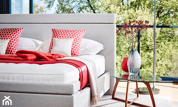 białe łóżko, czerwony koc, szklany stolik, beżowy dywan