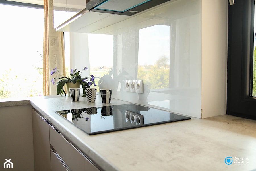 Kuchnia w kolorze ciepłego beżu - Mała zamknięta z kamiennym blatem biała z zabudowaną lodówką kuchnia w kształcie litery l z oknem, styl nowoczesny - zdjęcie od Dynarek MEBLE