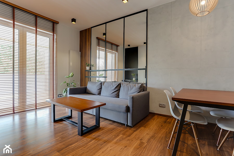 Mały salon z betonową ścianą oraz eleentami drewna i czerni. - zdjęcie od Atelier 37 | architektura & projektowanie wnętrz