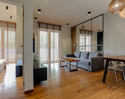 powiększony lustrami salon z betonową ściną oraz drewnianą podłogą - zdjęcie od Atelier 37 | architektura & projektowanie wnętrz - Homebook