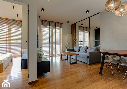 powiększony lustrami salon z betonową ściną oraz drewnianą podłogą - zdjęcie od Atelier 37 | architektura & projektowanie wnętrz