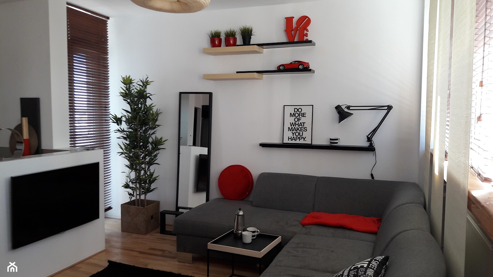 szary narożnik w małym salonie z białymi ścianami uzupełniony czerwonymi dekoracyjami - zdjęcie od Atelier 37 | architektura & projektowanie wnętrz - Homebook