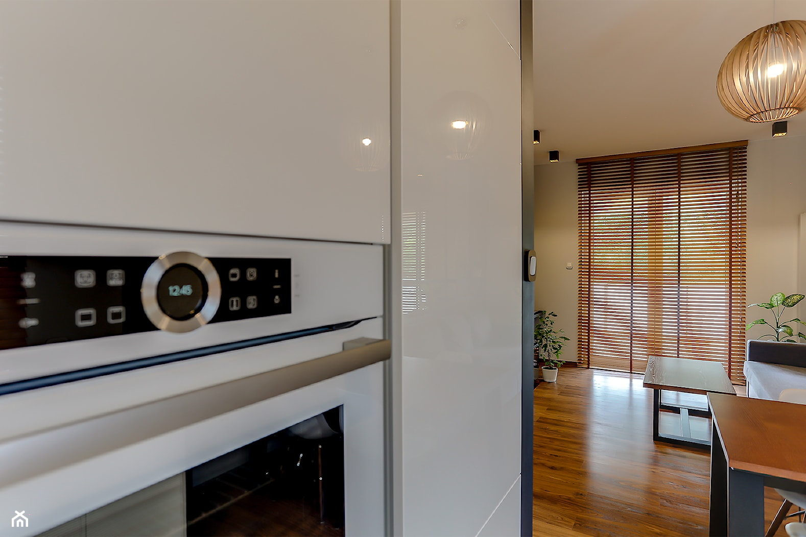 Biała kuchnia w ciepłym minimalistycznym salonie - zdjęcie od Atelier 37 | architektura & projektowanie wnętrz - Homebook