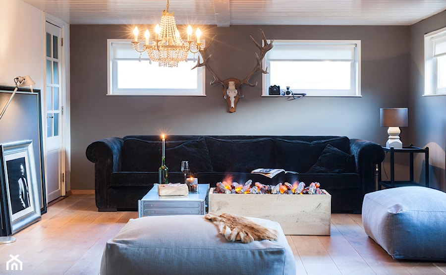 nowoczesny salon z kominkiem elektrycznym, czarna sofa, szare ściany, dekoracyjne poroże, drewniana podłoga