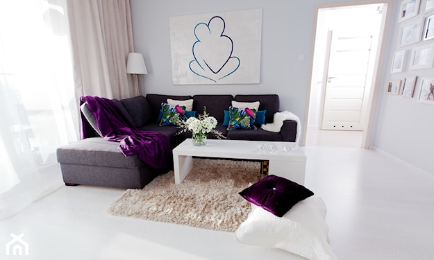 grafitowa sofa, fioletowa narzuta, zasłony w odcieniu pudrowego różu, beżowy dywan z długim włosiem