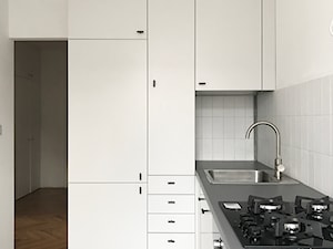 Średnia zamknięta z salonem biała z zabudowaną lodówką z nablatowym zlewozmywakiem kuchnia w kształcie litery l, styl skandynawski - zdjęcie od pigalopus