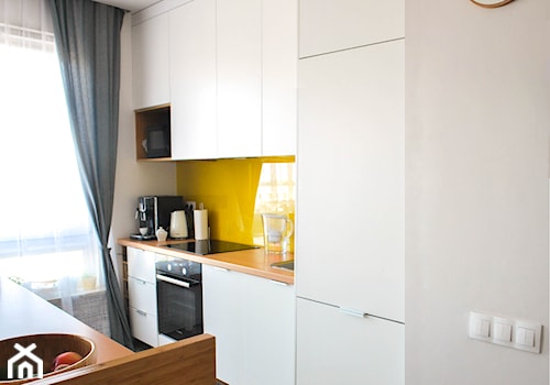 Mieszkanie dwupokojowe - Średnia otwarta z salonem biała żółta z zabudowaną lodówką z nablatowym zlewozmywakiem kuchnia jednorzędowa z wyspą lub półwyspem z oknem z kompozytem na ścianie nad blatem kuchennym, styl skandynawski - zdjęcie od kfprojekty
