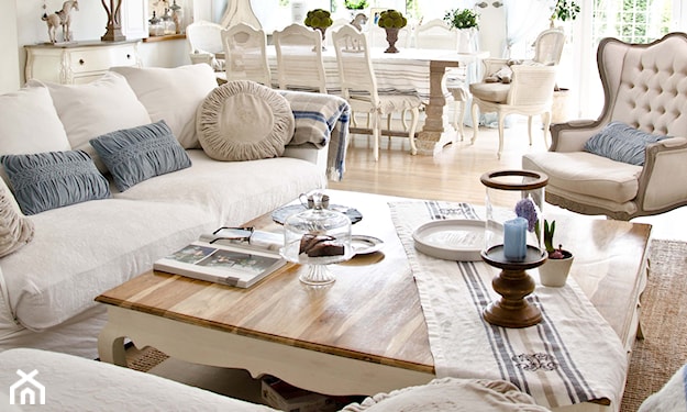kremowa sofa, beżowy pikowany fotel, drewniany stolik z ozdobnymi nóżkami, szare poduszki