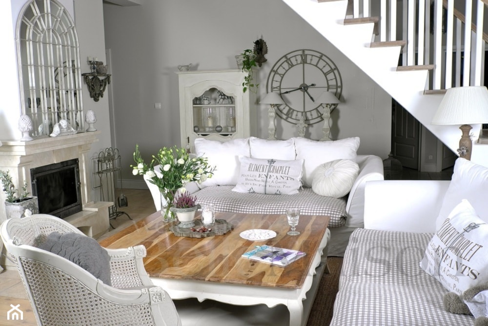 salon w stylu prowansalskim, kominek, drewniany stolik, biała sofa, zegar namalowany na ścianie