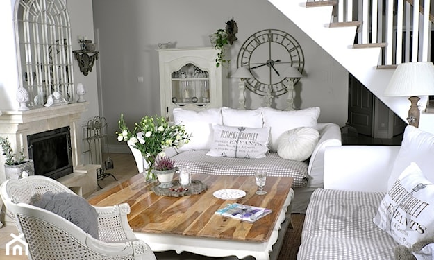 salon w stylu prowansalskim, biała sofa, narzuta w cienkie szare paski, kominek, zegar na ścianie