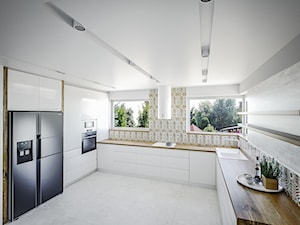 Przestronna biała kuchnia - Duża otwarta z salonem beżowa biała z zabudowaną lodówką z lodówką wolnostojącą z nablatowym zlewozmywakiem kuchnia w kształcie litery u z oknem, styl skandynawski - zdjęcie od Vimko Projektowanie Wnętrz