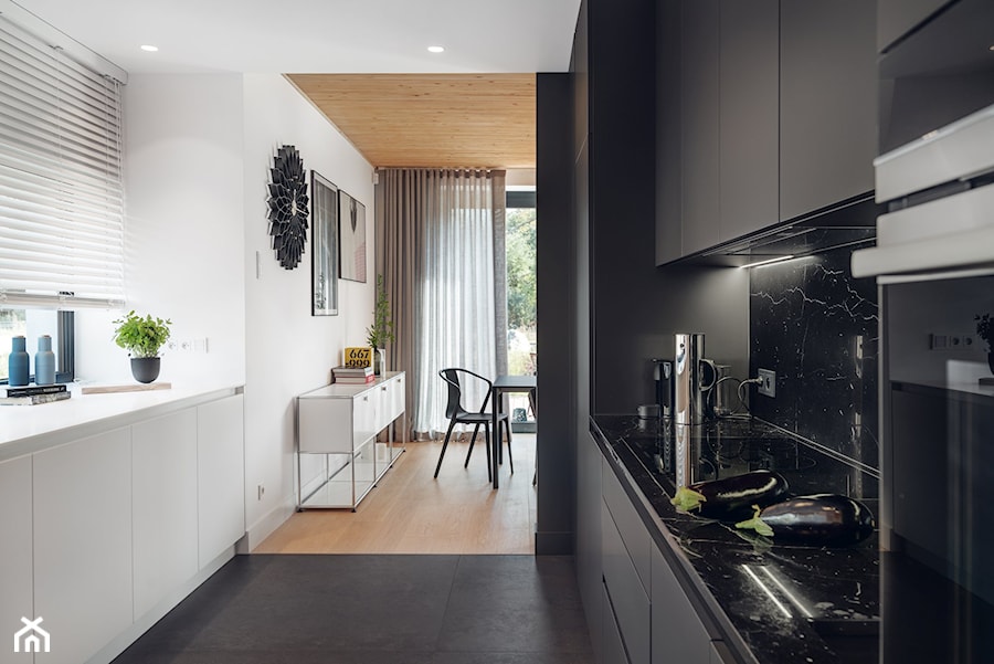 Ekorezydencja - Średnia otwarta biała czarna z zabudowaną lodówką z lodówką wolnostojącą kuchnia dwurzędowa z oknem z marmurem nad blatem kuchennym, styl nowoczesny - zdjęcie od Ev Architects