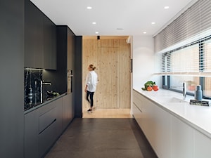 Ekorezydencja - Średnia otwarta biała czarna z zabudowaną lodówką z podblatowym zlewozmywakiem kuchnia dwurzędowa z oknem z marmurem nad blatem kuchennym, styl nowoczesny - zdjęcie od Ev Architects