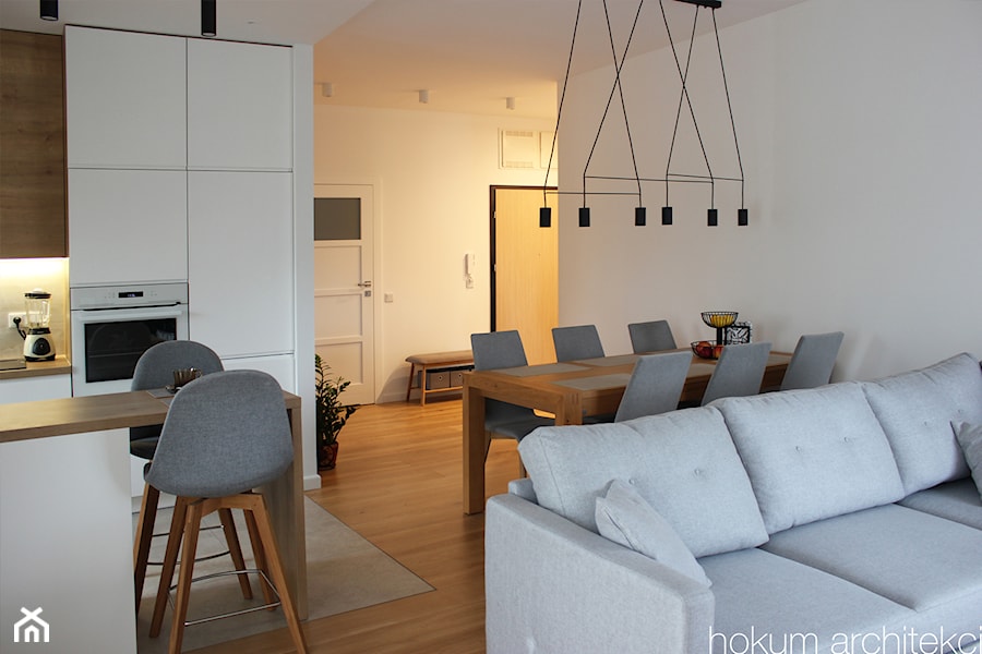 Mieszkanie z widokiem na wodę, 70m2 - Biały salon z kuchnią z jadalnią, styl skandynawski - zdjęcie od Hokum Architekci