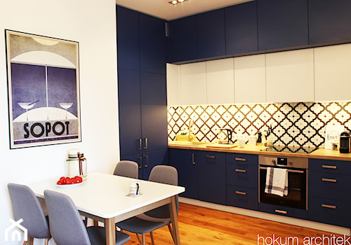 Mieszkanie w odcieniach błękitu 43m2 - Średnia zamknięta biała z zabudowaną lodówką z nablatowym zlewozmywakiem kuchnia z granatowymi frontami w kształcie litery l, styl skandynawski - zdjęcie od Hokum Architekci