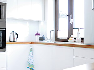 Biała kuchnia z drewnem. - Mała otwarta zamknięta biała z zabudowaną lodówką kuchnia w kształcie litery l, styl nowoczesny - zdjęcie od Joanna Stelmaszczuk Projektowanie Wnętrz