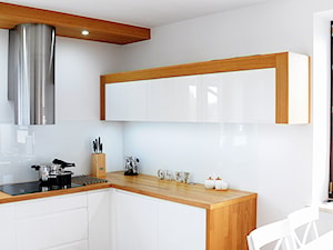 Biała kuchnia z drewnem. - Średnia otwarta biała z zabudowaną lodówką kuchnia w kształcie litery l, styl nowoczesny - zdjęcie od Joanna Stelmaszczuk Projektowanie Wnętrz